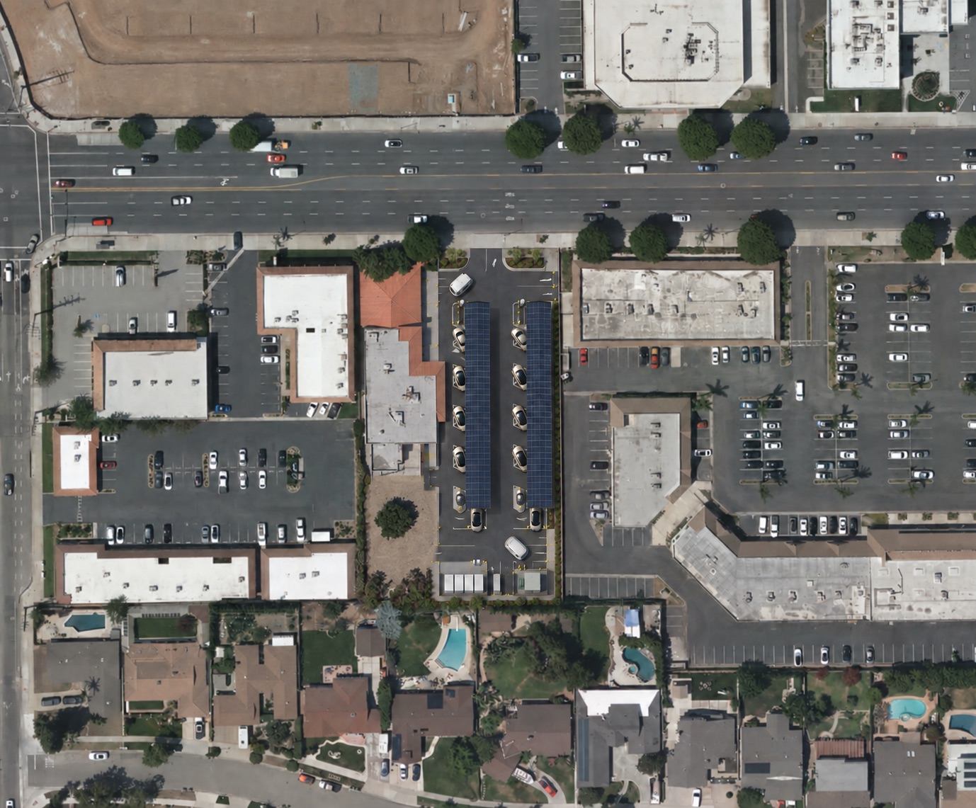 Site-based concept for 1010 E Katella Avenue: existing west-side building, proposed charging in the eastern yard, Katella Avenue to the north and homes to the south